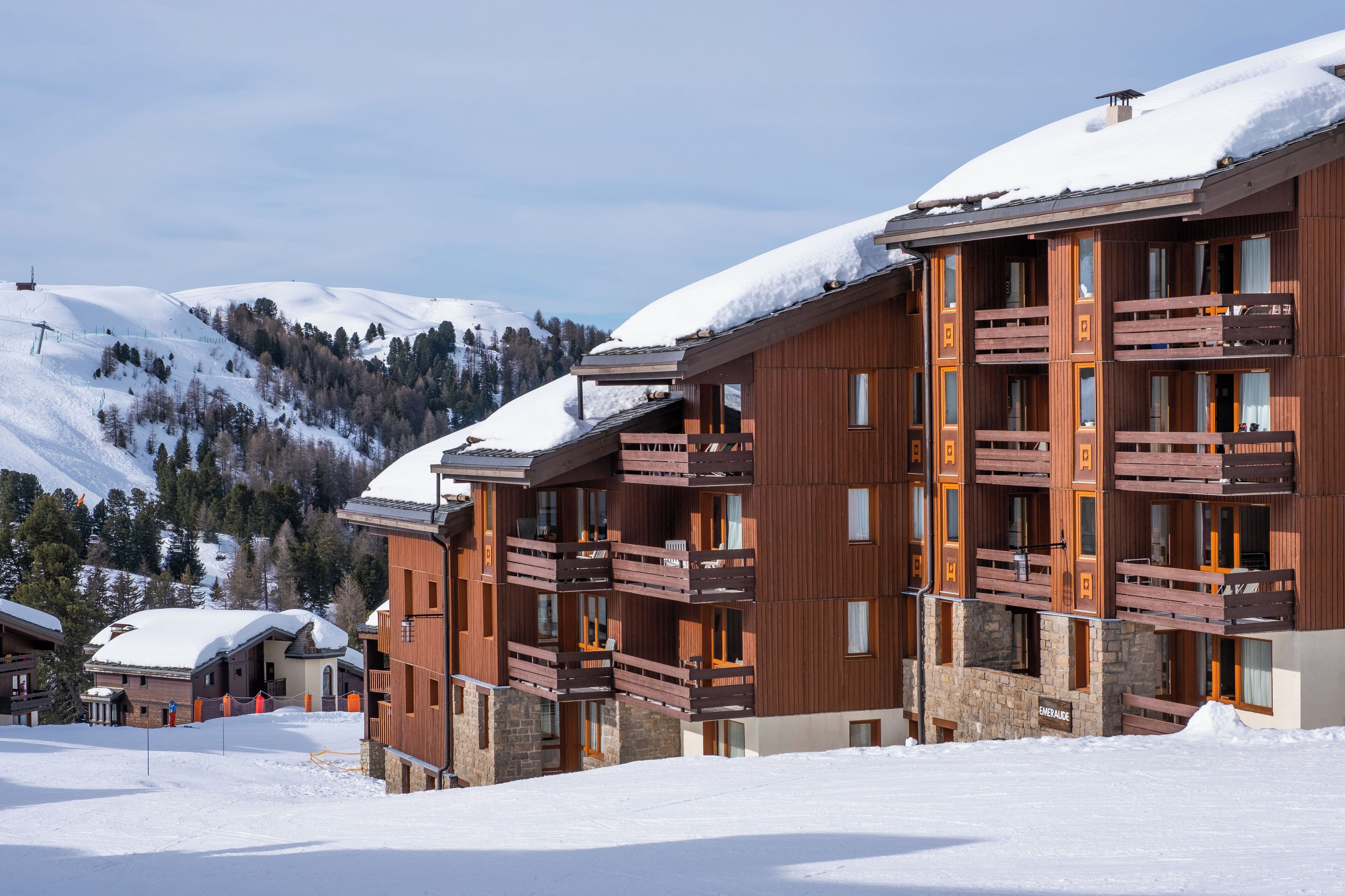 A multi-story hotel with wooden balconies and a snow-covered landscape.
