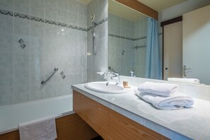 Uma casa de banho moderna com banheira, lavatório, espelho e chuveiro.
