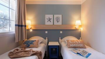Een hotelkamer met twee bedden, een nachtkastje, een lamp en twee foto's aan de muur.