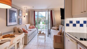 A modern living room with a sofa, dining table, and kitchen area. - Résidence Pierre & Vacances Cap Marine (Guilvinec)