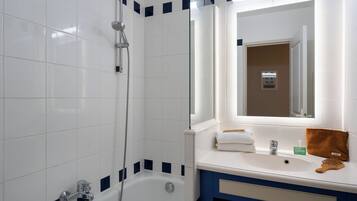 A bathroom with white tiles, a bathtub, a shower, a sink with a mirror, and a towel rack.