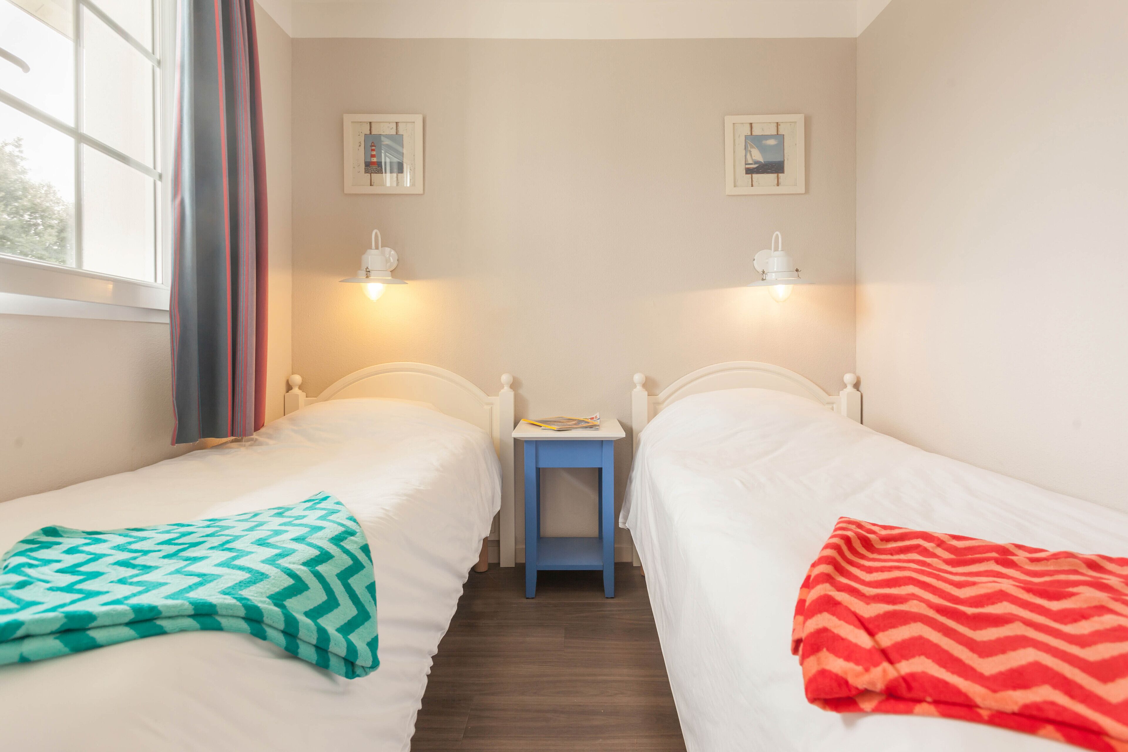 Een kamer met twee bedden, een klein tafeltje en twee wandlampen.