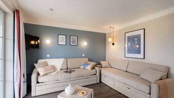 A modern living room with two sofas, a coffee table, and wall-mounted lights.