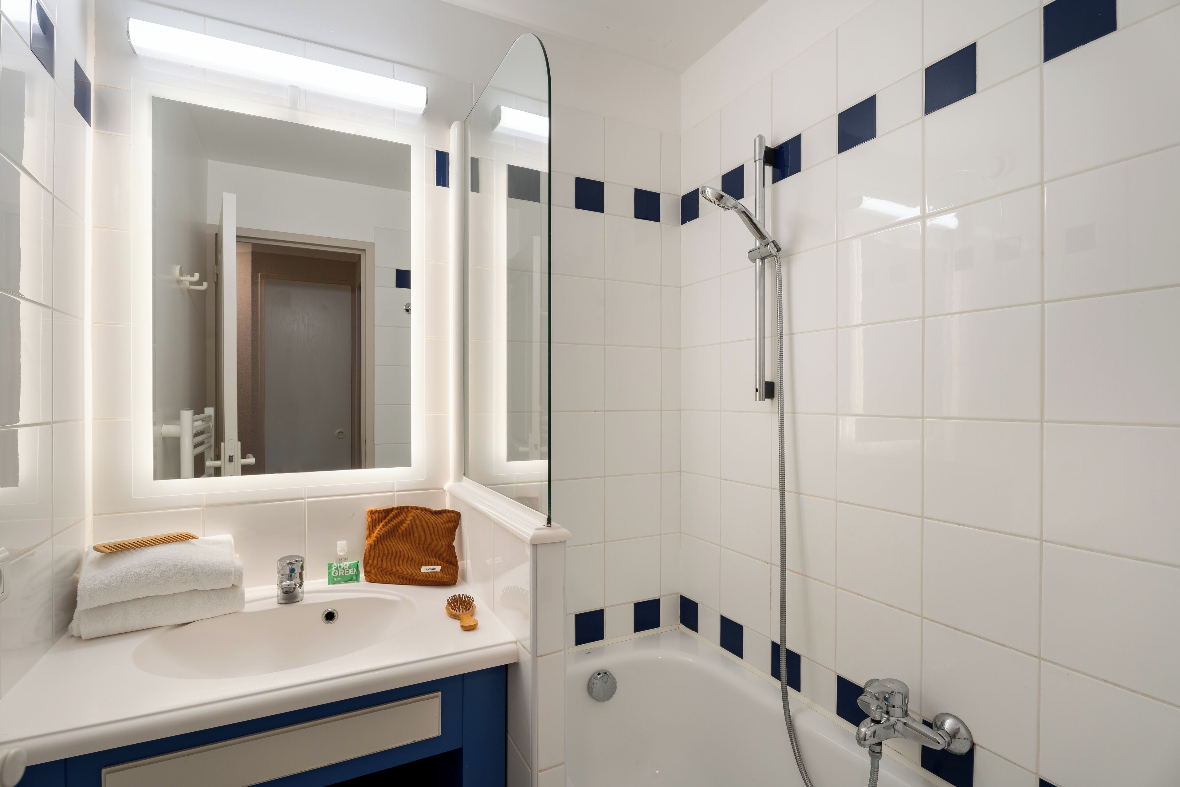 Une salle de bain avec un lavabo blanc, un miroir et une douche.