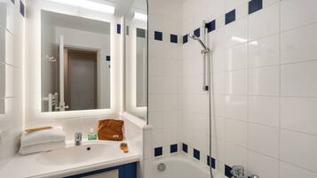 Une salle de bain avec un lavabo blanc, un miroir et une douche.