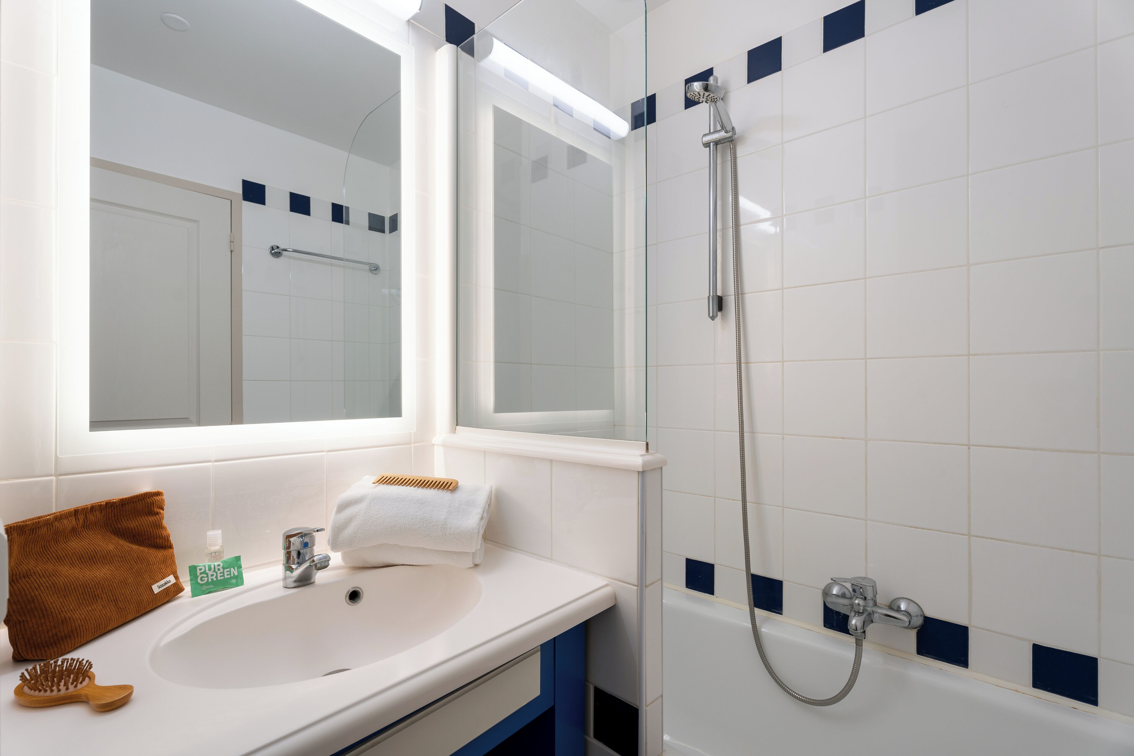 Een badkamer met een wit wastafel, een spiegel, een handdoek en een douche.