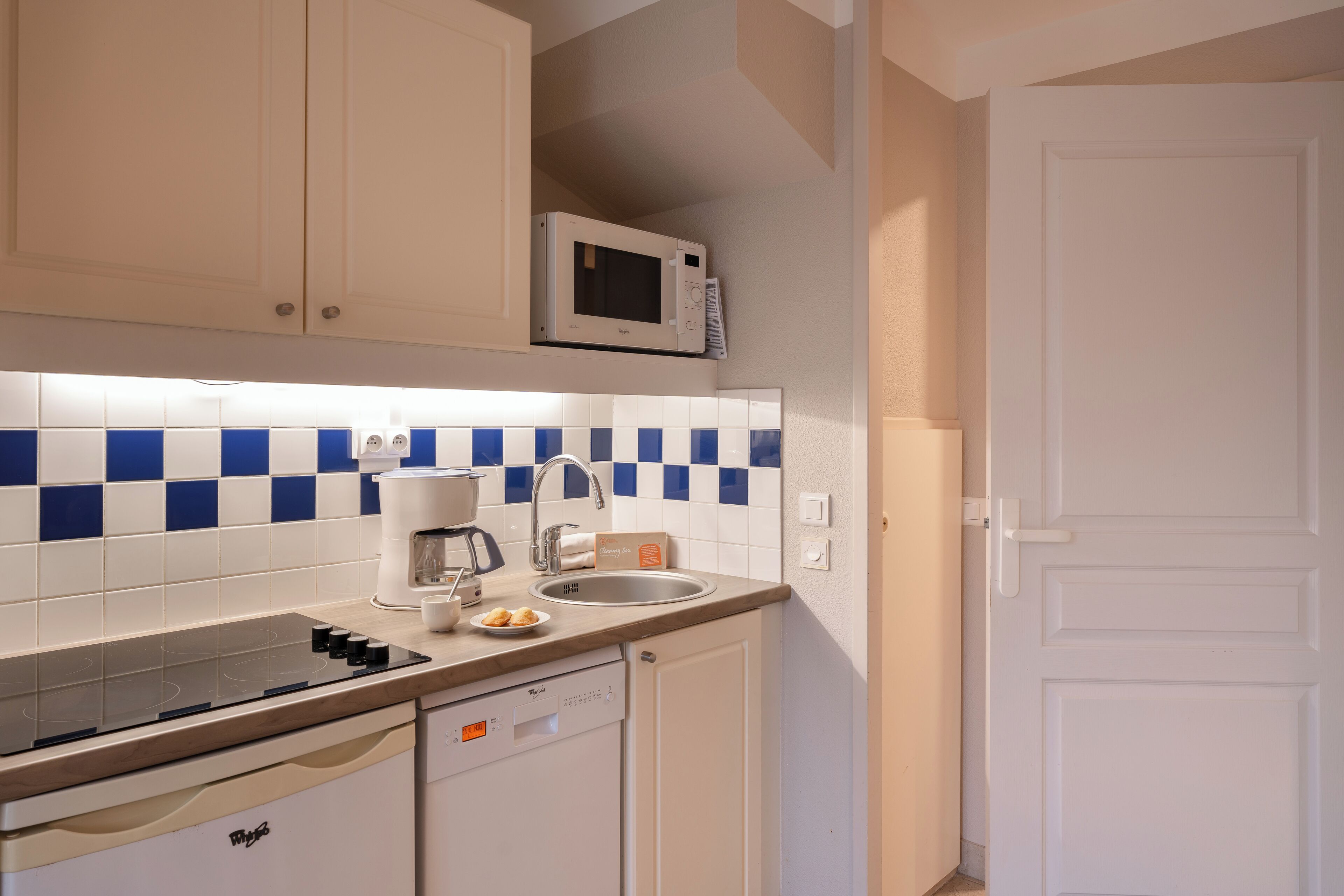 A compact kitchen with a microwave, coffee maker, and dishwasher.