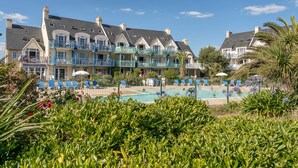 A hotel with multiple balconies, a swimming pool, and lush greenery. - Résidence Pierre & Vacances Cap Marine (Guilvinec)