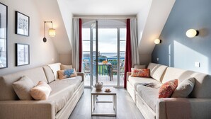 A modern living room with two sofas, a coffee table, and a view of the outdoors through a glass door. - Résidence Pierre & Vacances Cap Marine (Guilvinec)