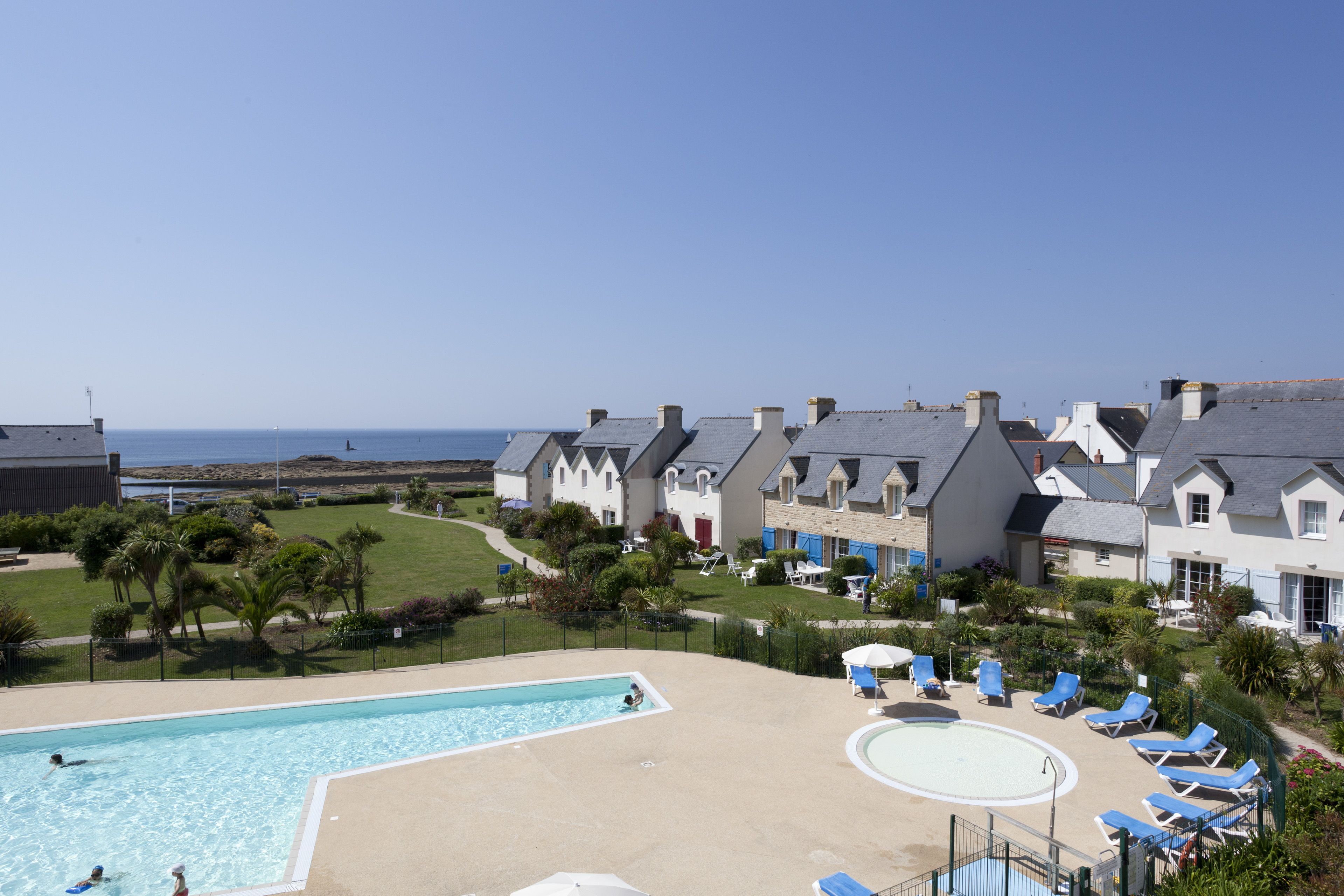Un hôtel doté d’une piscine, de chaises longues et offrant une vue sur la mer.