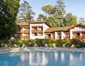 A resort with a swimming pool, multiple balconies, and lush greenery.