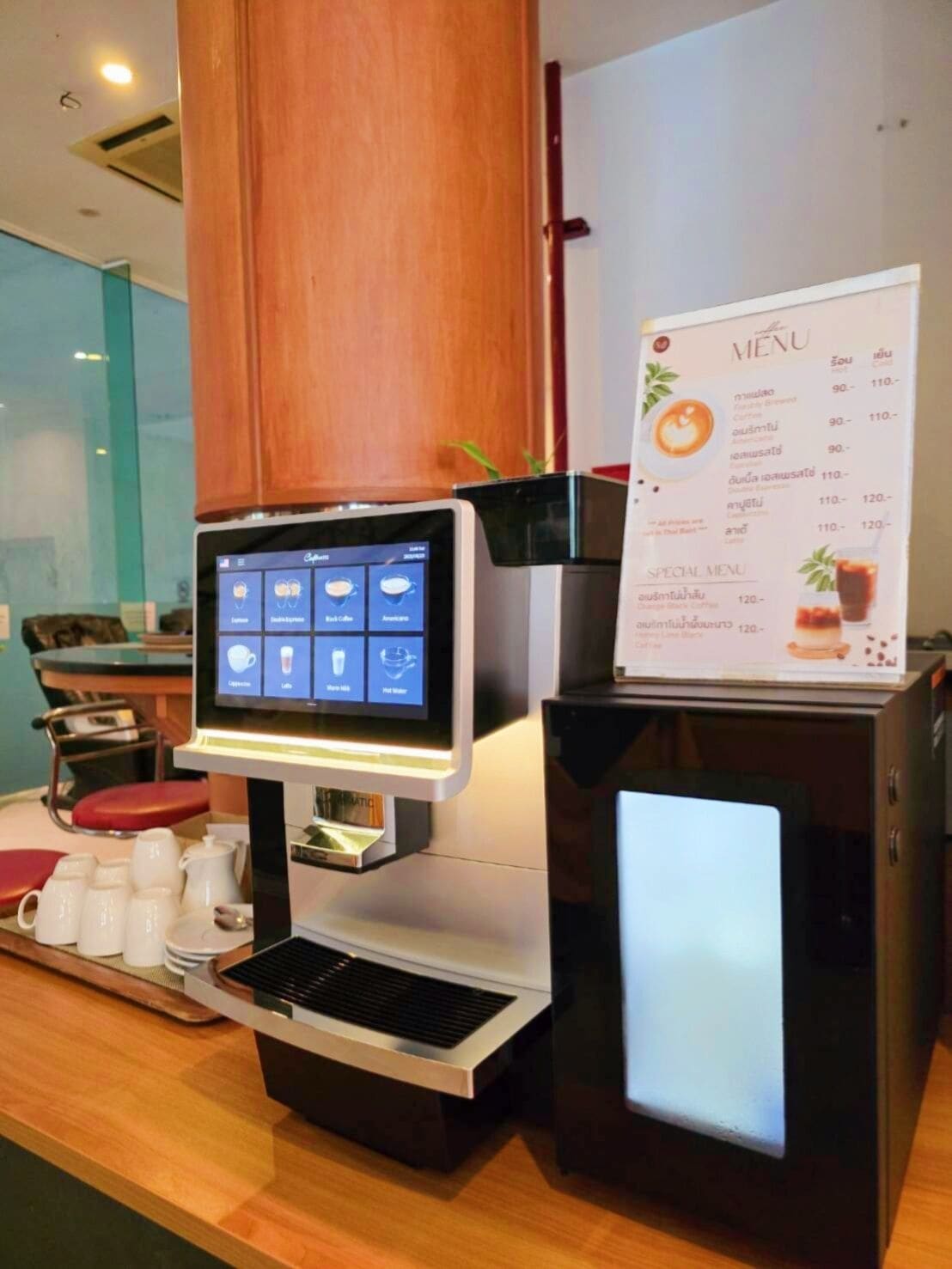 Eine Kaffeemaschine mit digitalem Display und einer Speisekarte in einem Café.