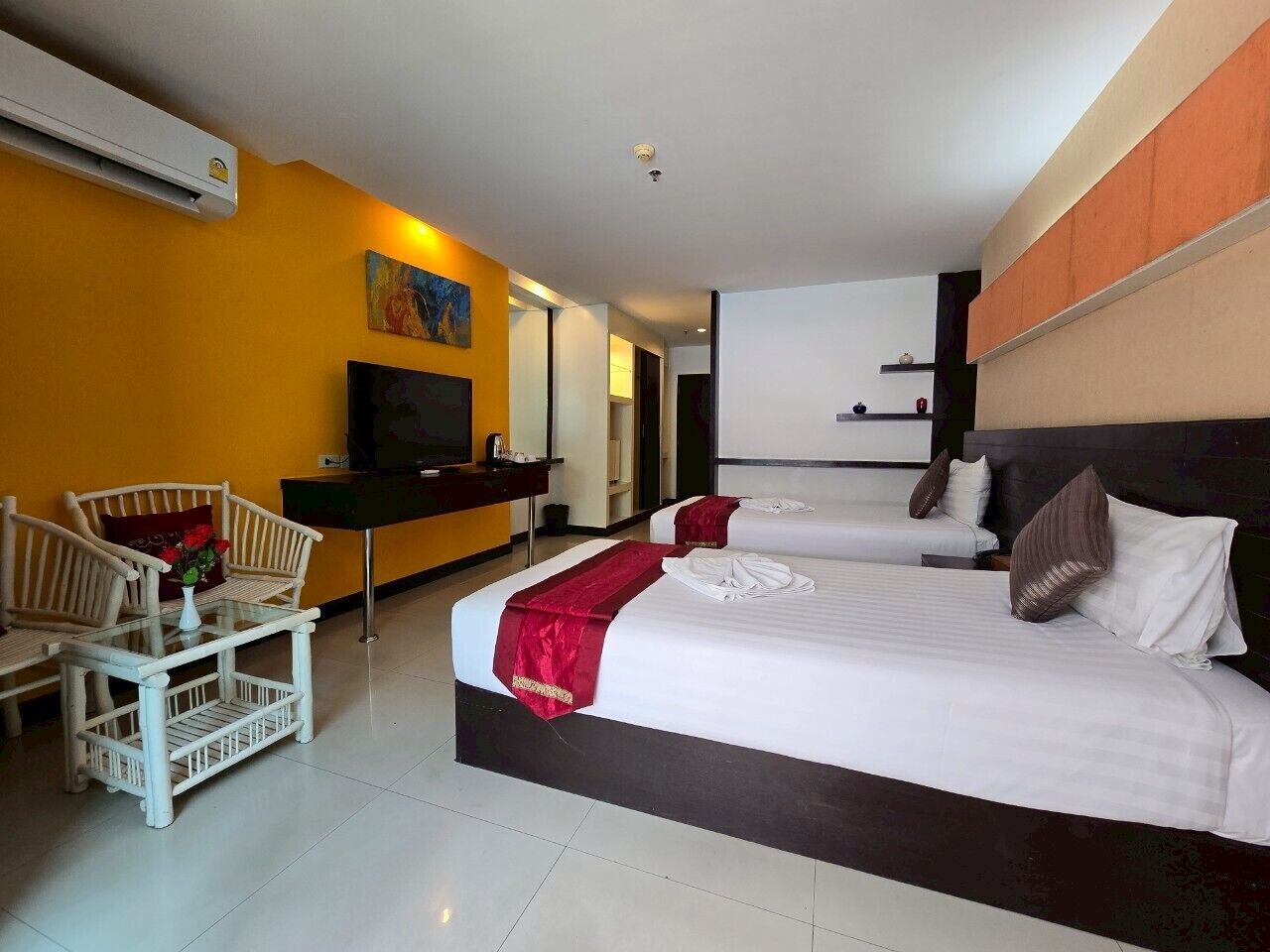 A hotel room with two beds, a desk, a chair, and a television.