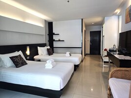 Quarto de hotel com duas camas, uma escrivaninha, uma cadeira e uma televisão.