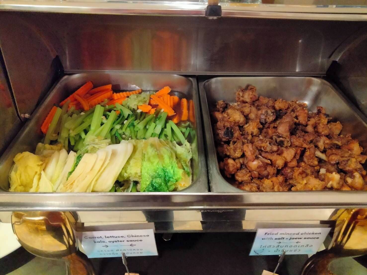 Un bufé con diversos platos, entre ellos zanahorias, lechuga, col china y salsa de ostras.