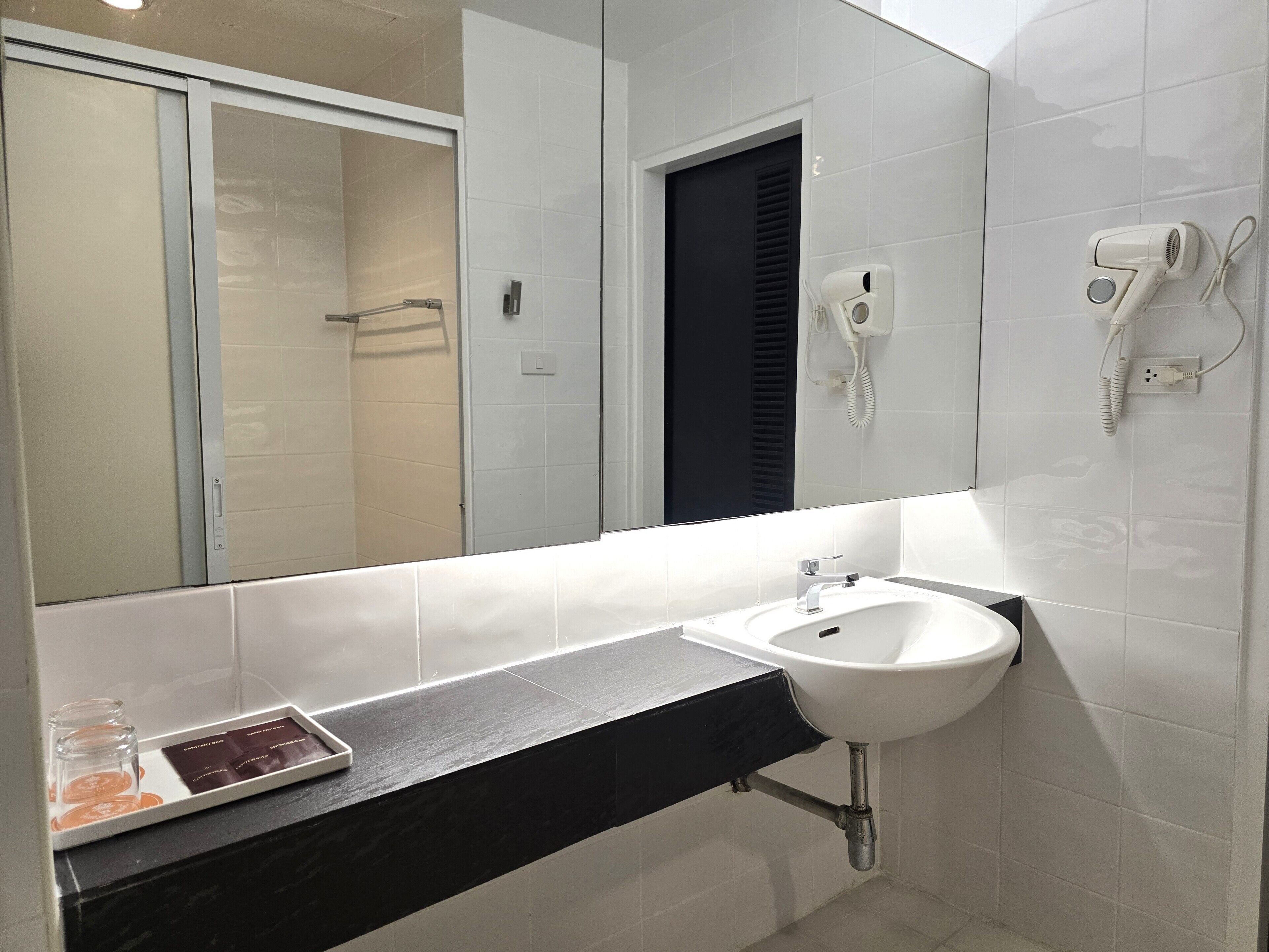 A bathroom with a sink, mirror, and hairdryer.