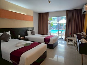 Quarto de hotel com duas camas, uma escrivaninha e vista para uma piscina ao ar livre.