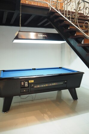 Enjoy a game of pool in this stylish room with a billiards table and staircase leading to an upper level.