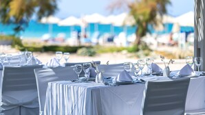 A table set for a meal with a view of the beach and umbrellas in the background.