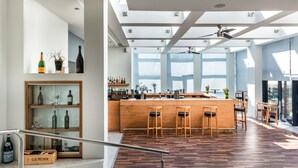A modern bar area with wooden stools, a bar counter, and a glass display case with bottles.