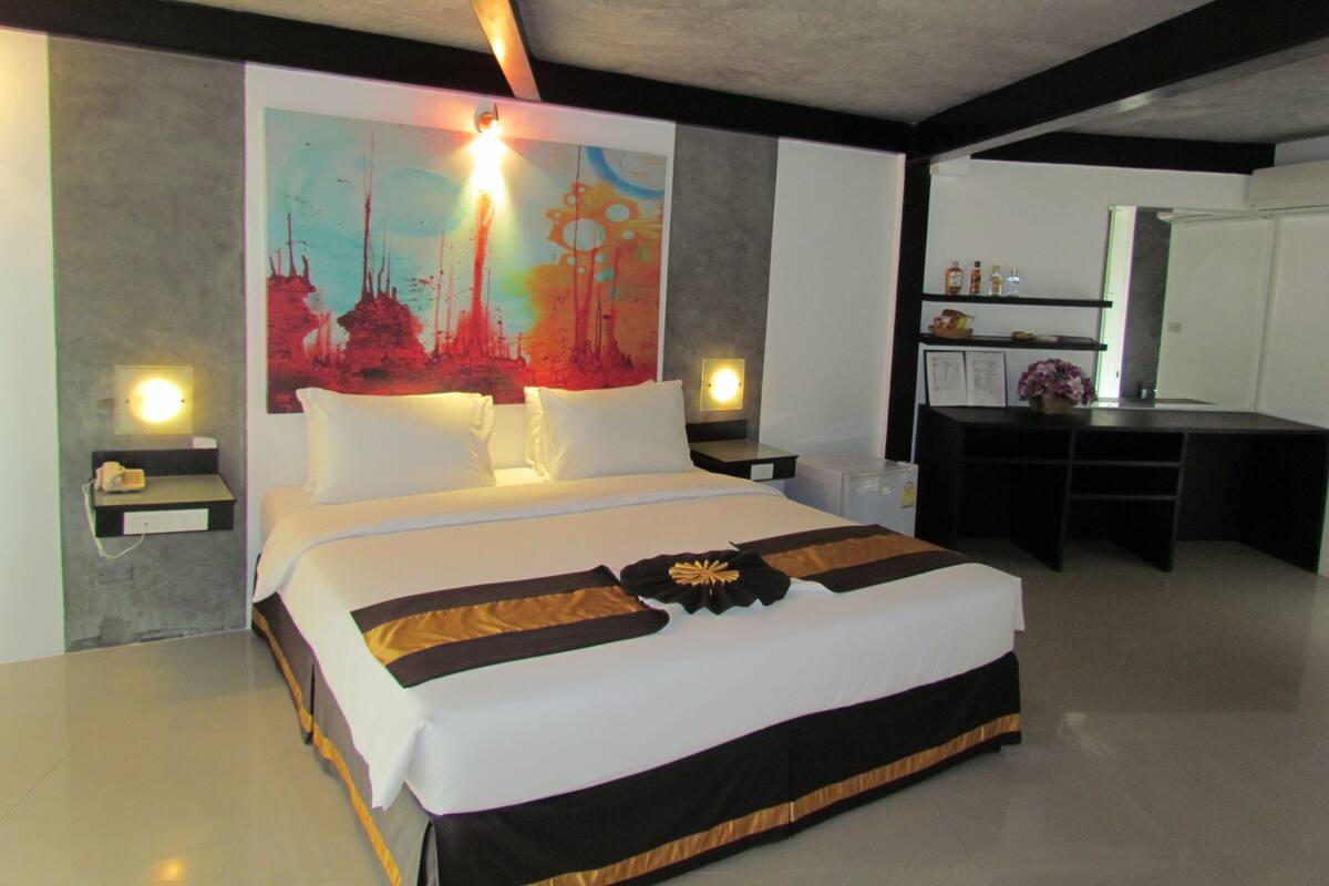 Una habitación de hotel moderna con una cama grande, un escritorio y un baño.
