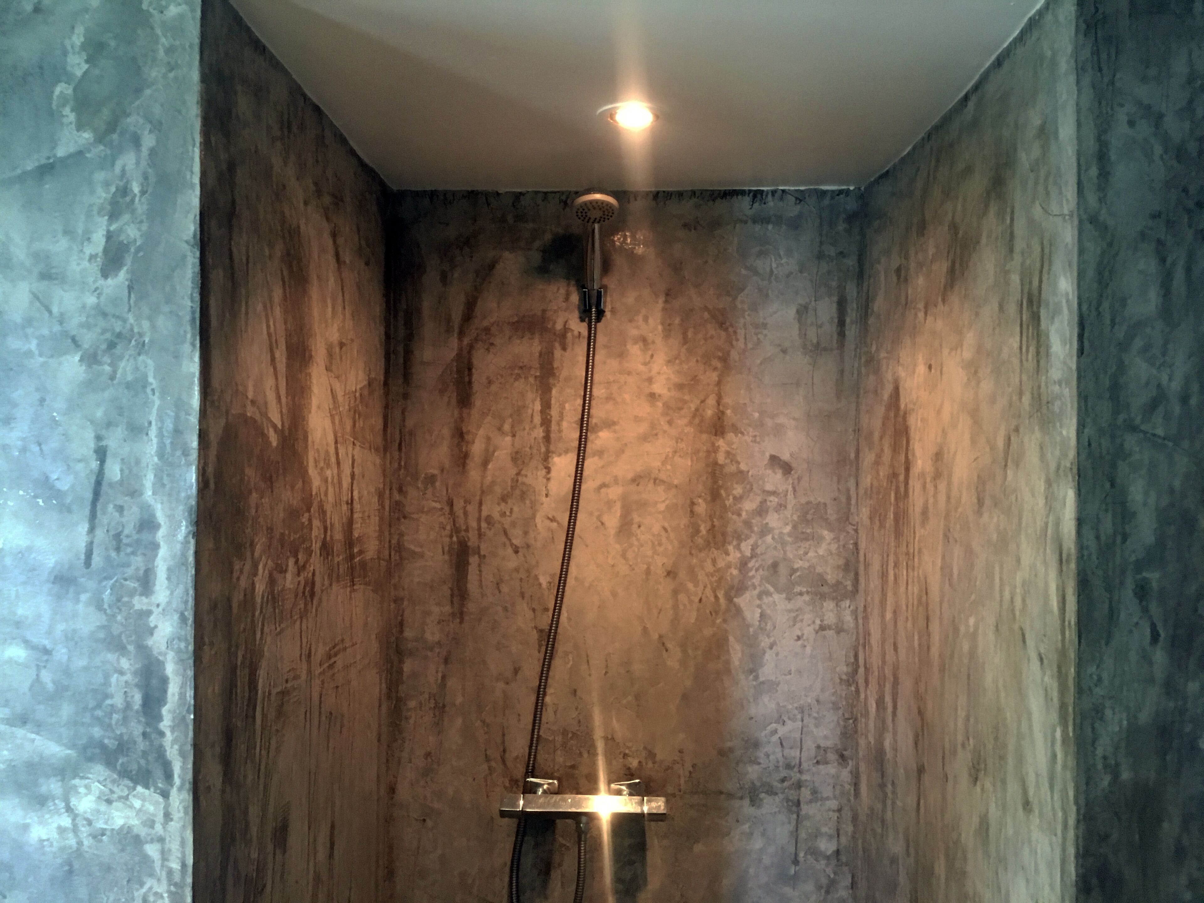 A shower with a chain and a light fixture above it.