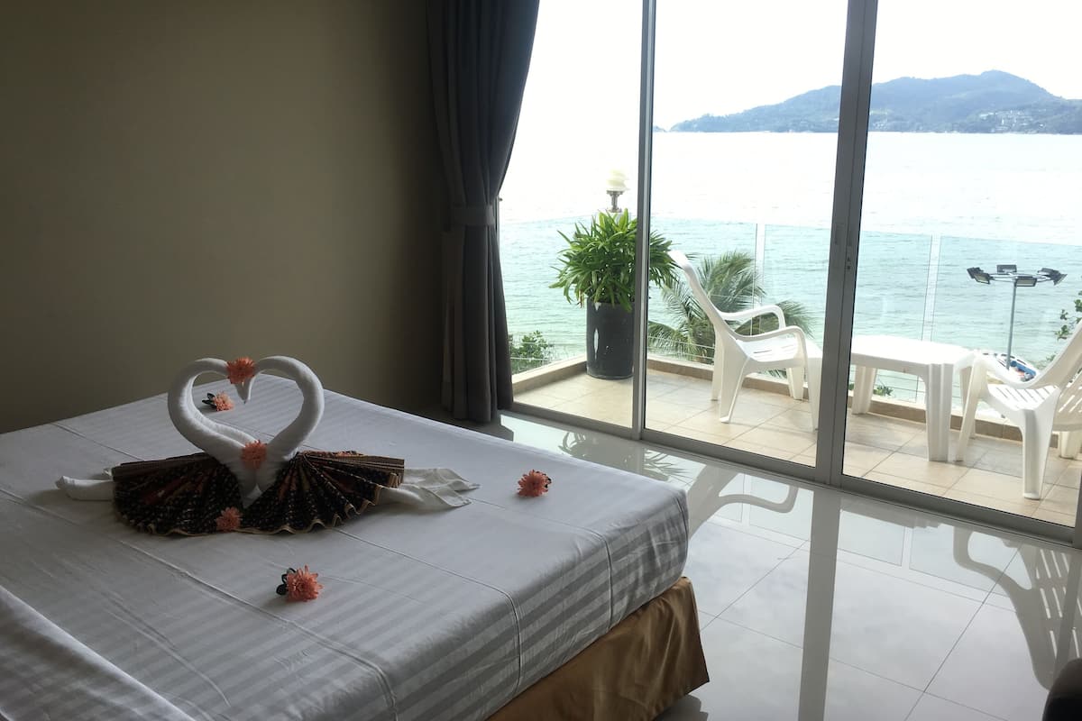Habitación de hotel con cama, balcón y vista al mar, además de una planta en maceta.