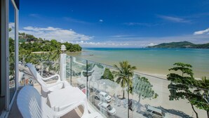 A balcony with white chairs overlooking a beach with clear blue water and a few boats. - The Front Hotel and Apartment (Patong)