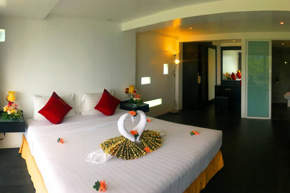 Habitación de hotel con una cama grande, un televisor y un baño visible a través de una puerta abierta.