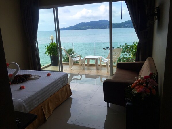 A hotel room with a balcony overlooking a body of water and hills. - The Front Hotel and Apartment (Patong)
