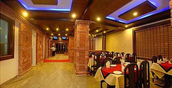 A restaurant with brick walls, wooden ceiling, and tables set for dining.