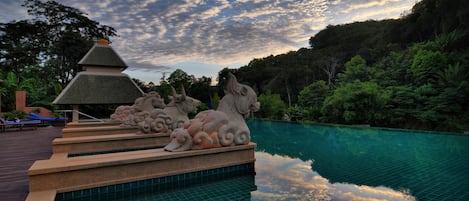 A serene pool area with stone sculptures and a clear view of the sky.