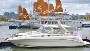 A white boat with orange sails docked at a marina. - Paradise Peak Cruise (Tuan Chau)