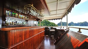 A wooden bar area with a view of the water and mountains. - Paradise Peak Cruise (Tuan Chau)