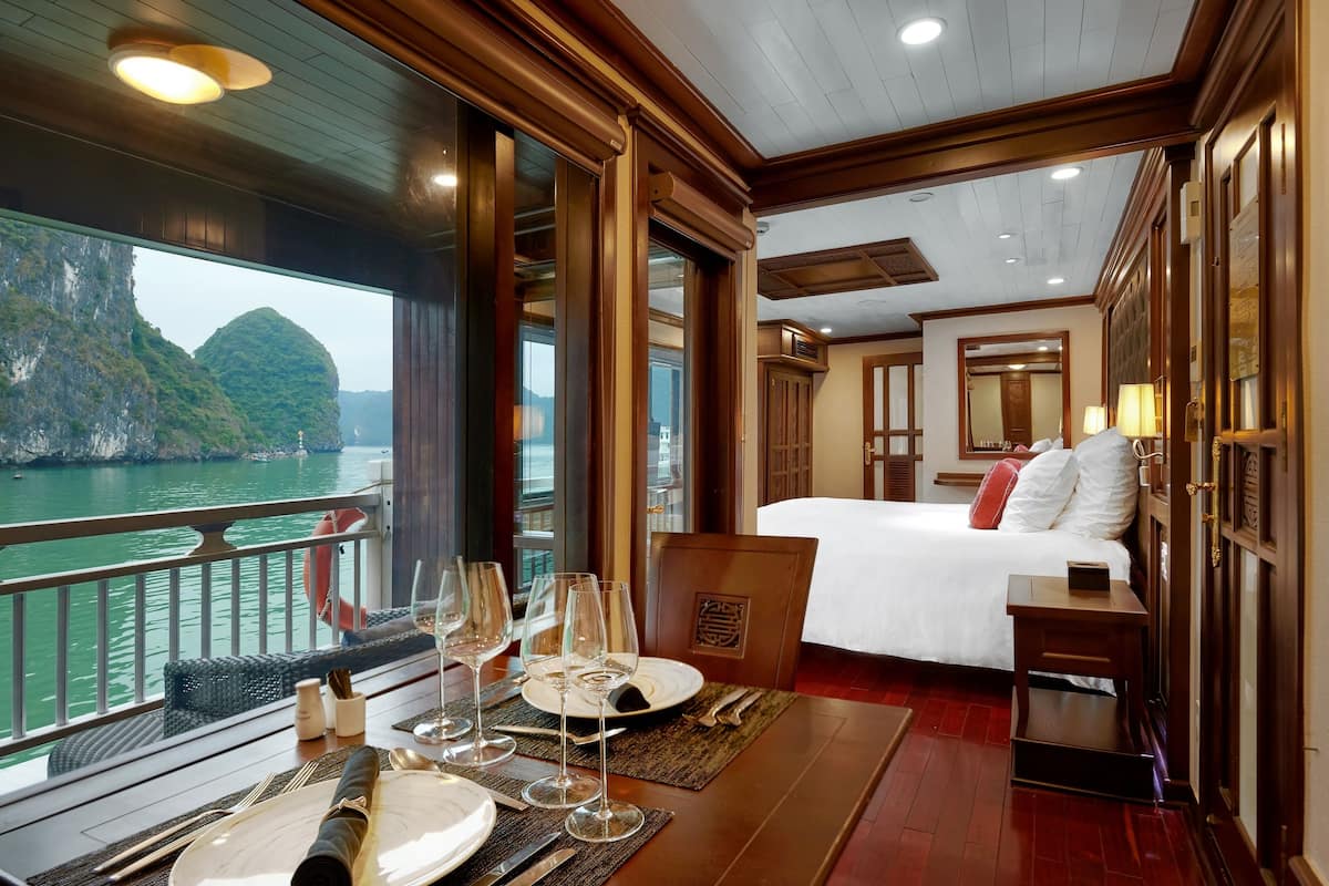 A room with a bed, bedside table, and a view of a body of water.