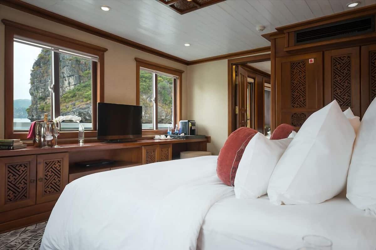 A hotel room with a large bed, wooden headboard, and a television on a wooden desk.