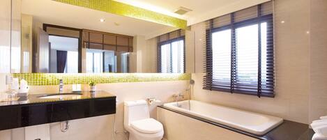 A modern bathroom with a black countertop, a white toilet, a bathtub, and a large mirror.