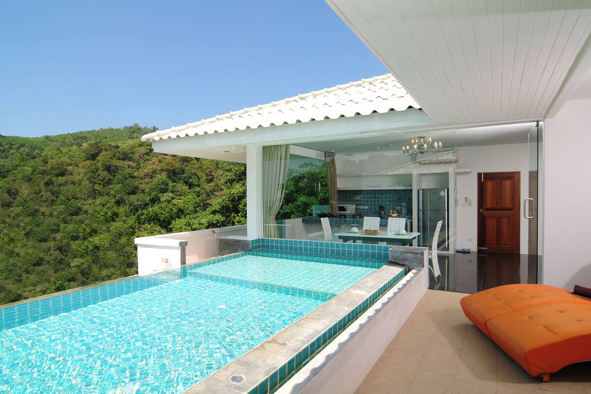 A modern outdoor pool area with a clear view of a lush green hillside.