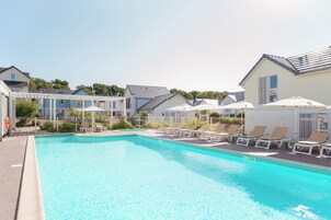 Una piscina techada, una piscina al aire libre de temporada, sombrillas