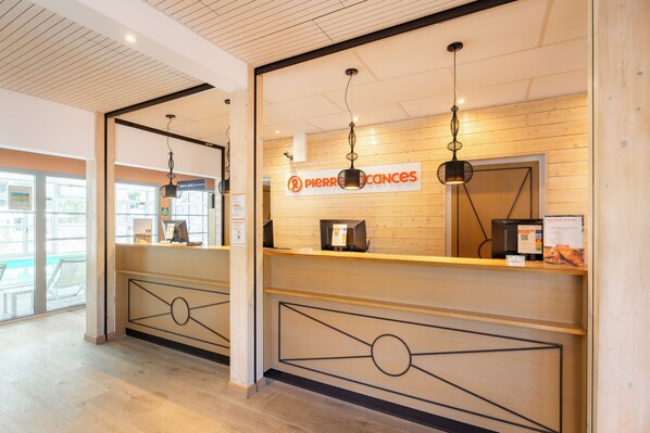 A reception area with a wooden counter, overhead lighting, and a sign indicating a bar and games area.