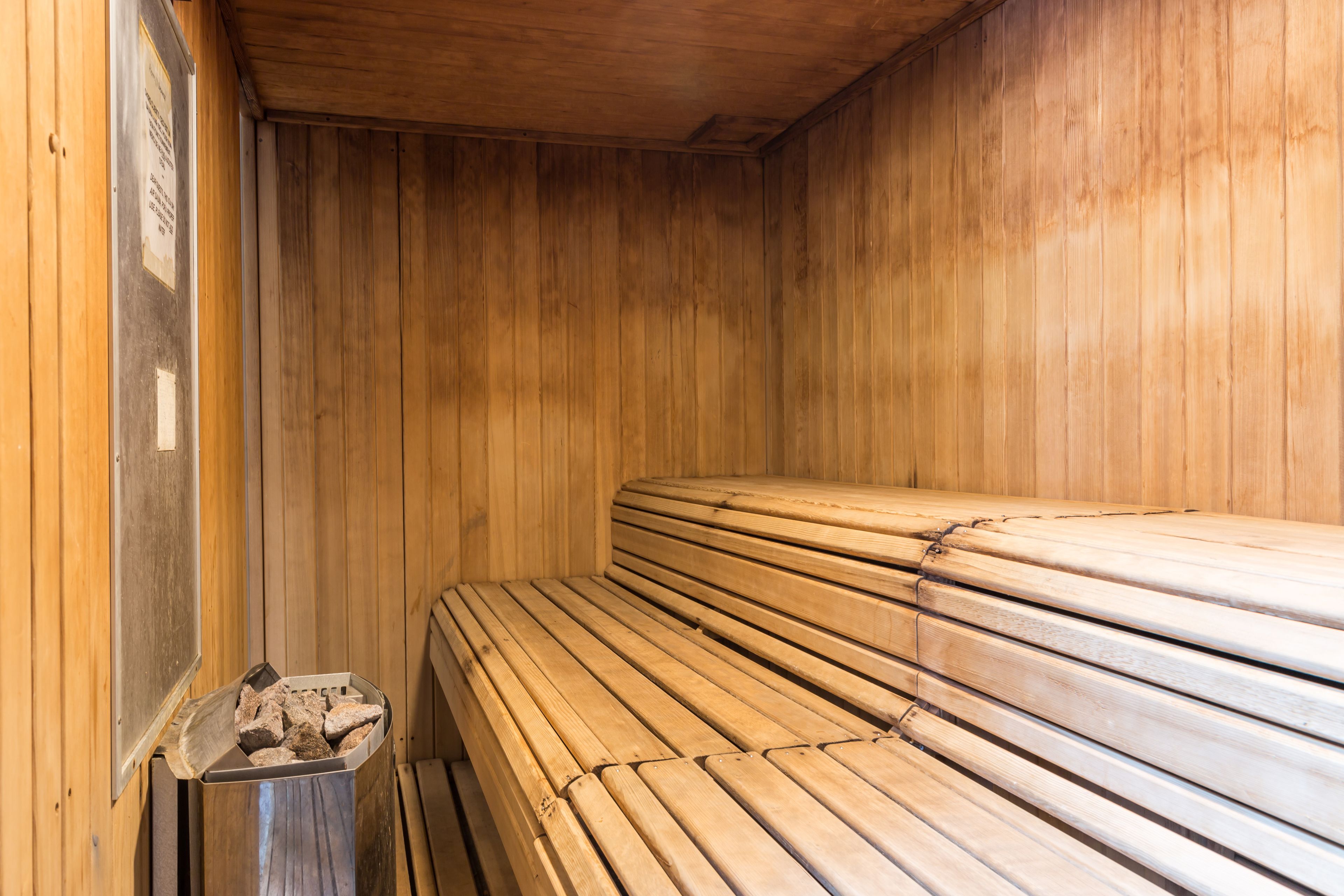 Un sauna avec des bancs en bois et une poubelle.