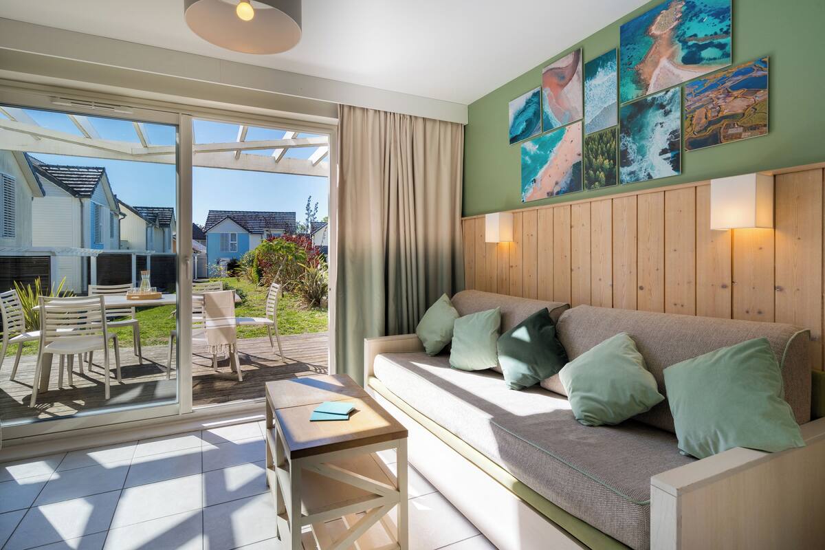 Un salon moderne avec un canapé, des coussins, une table et une vue sur l’extérieur.