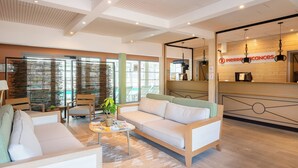 Una sala de estar moderna con un sofá, sillas, una mesa de centro y un ventanal grande.