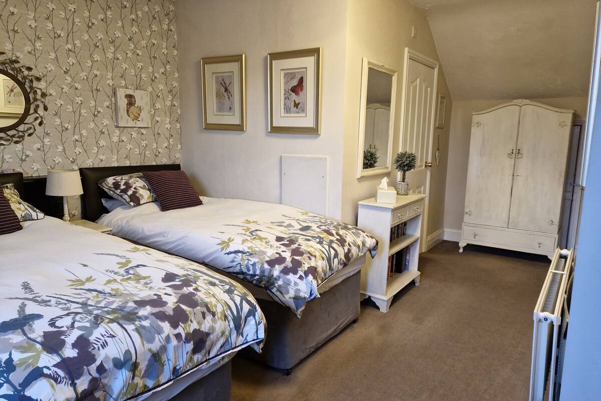 Une chambre avec deux lits, une commode, un miroir et une armoire.