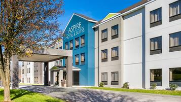 Un hotel moderno con fachada azul y blanca, múltiples ventanas y una zona de entrada cubierta.