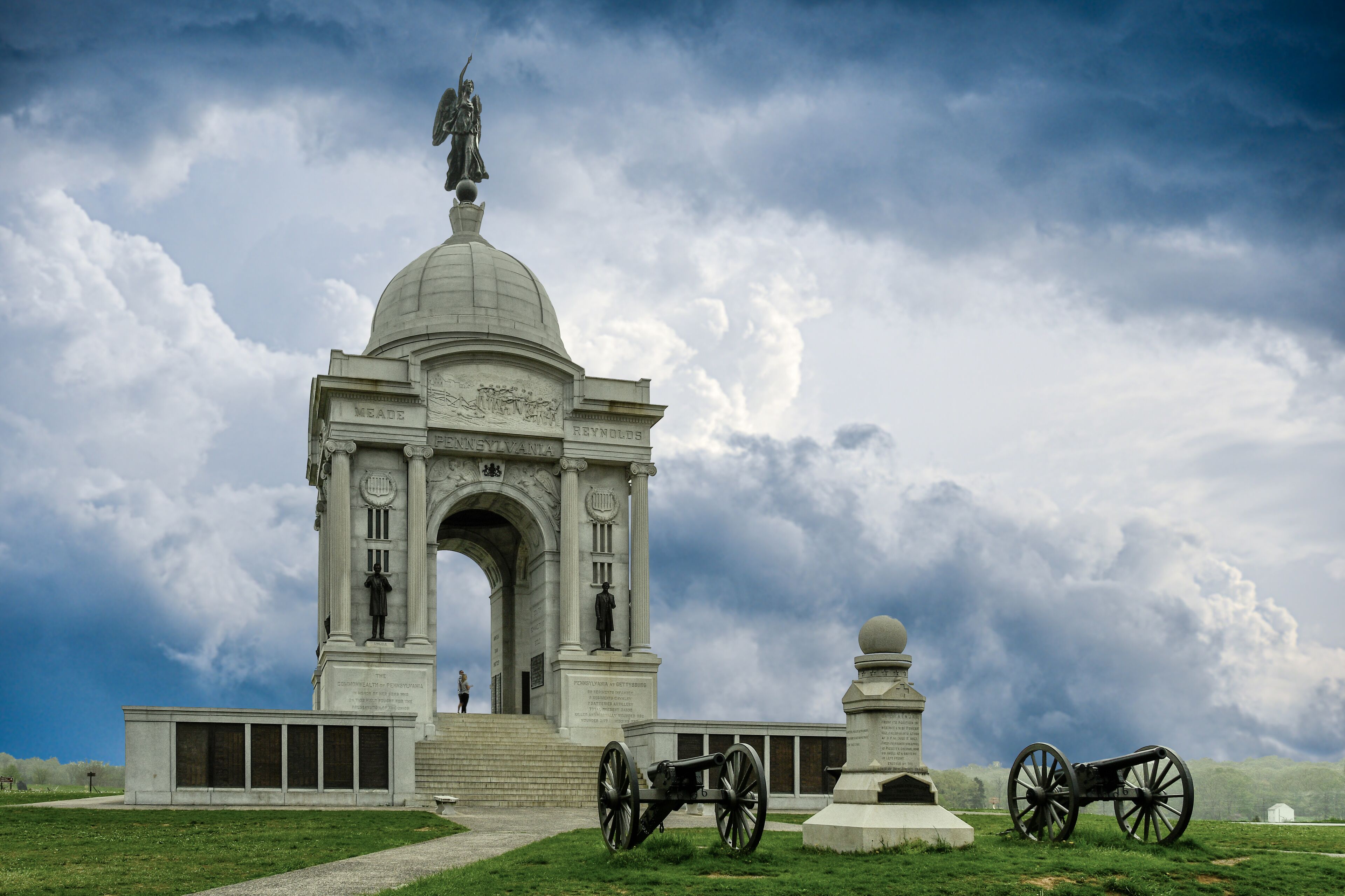 Un monument historique doté d’une grande arche, d’une statue au sommet et d’un canon en premier plan.