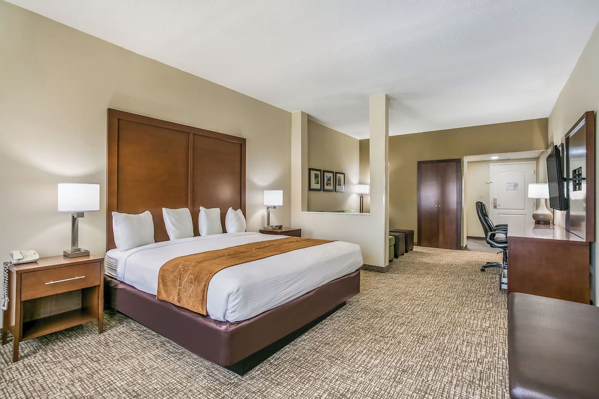 A hotel room with a large bed, bedside tables, a desk, and a chair.
