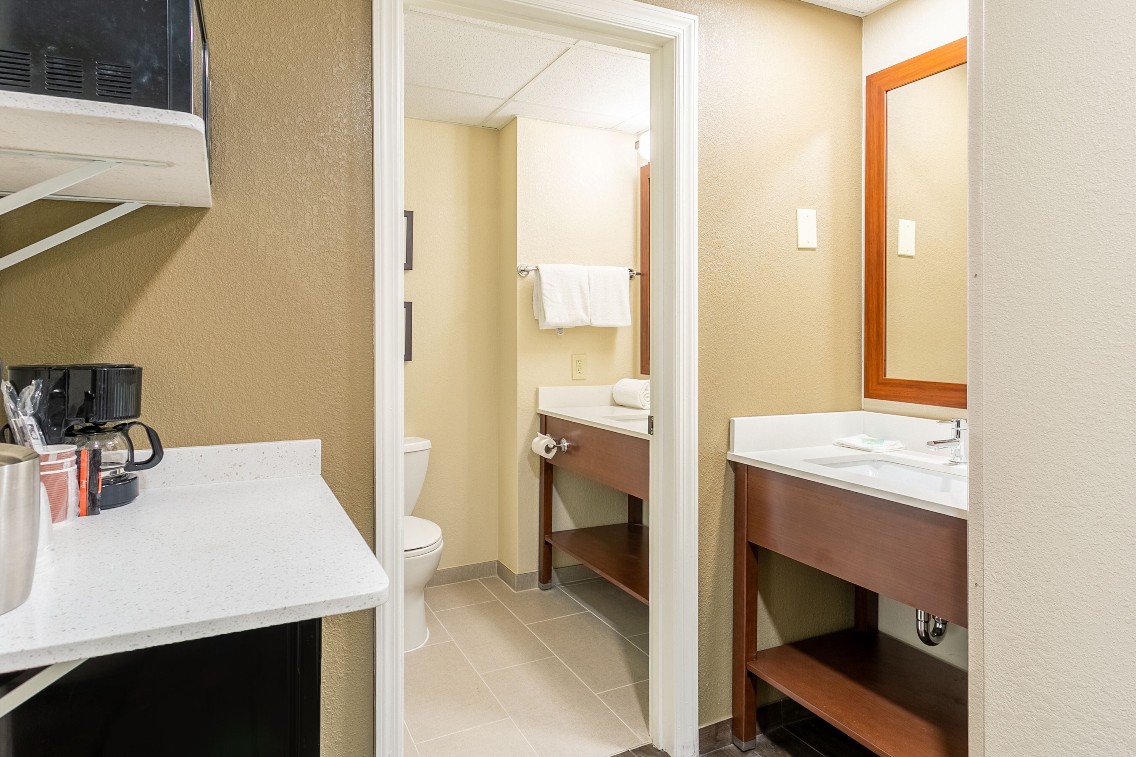 Un baño de hotel con un lavamanos blanco, un espejo, un inodoro y una zona de ducha.