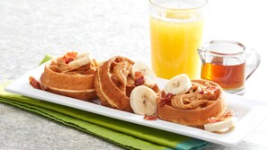 A breakfast plate with pancakes, bananas, and bacon, accompanied by a glass of orange juice and a mug of tea. - Aspire Gettysburg Hotel (Gettysburg)