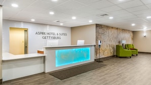 A hotel reception area with a modern design, including a reception desk, a green chair, and a wall map. - Aspire Gettysburg Hotel (Gettysburg)